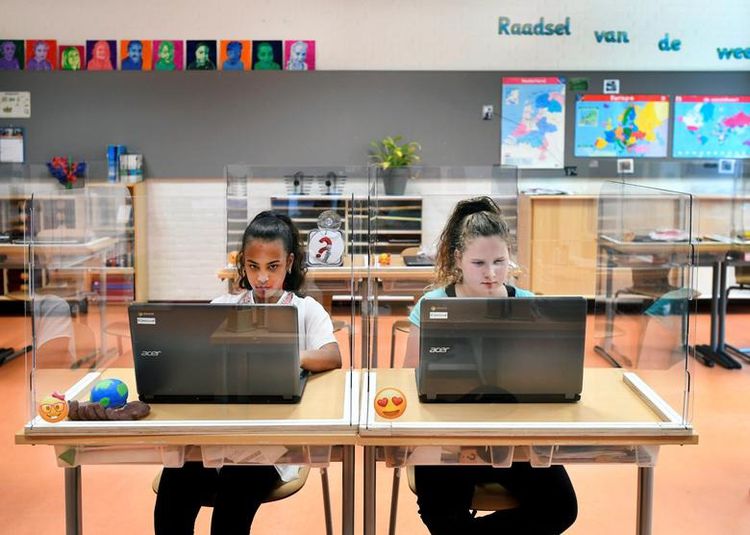 Учні сидять за дошками перегородки з оргскла, відвідуючи заняття в початковій школі в Den Bosch, Нідерланди
