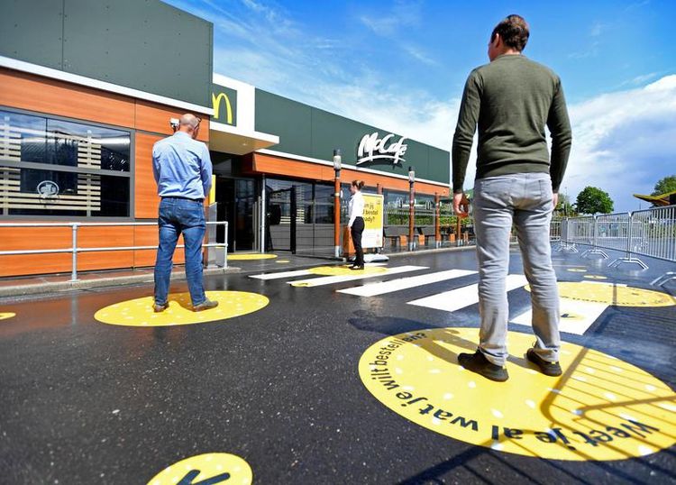 Клієнти чекають на вулиці, стоячи на маркованих відрізках соціального дистанціювання перед будівлею McDonald's в Арнем, Нідерланди